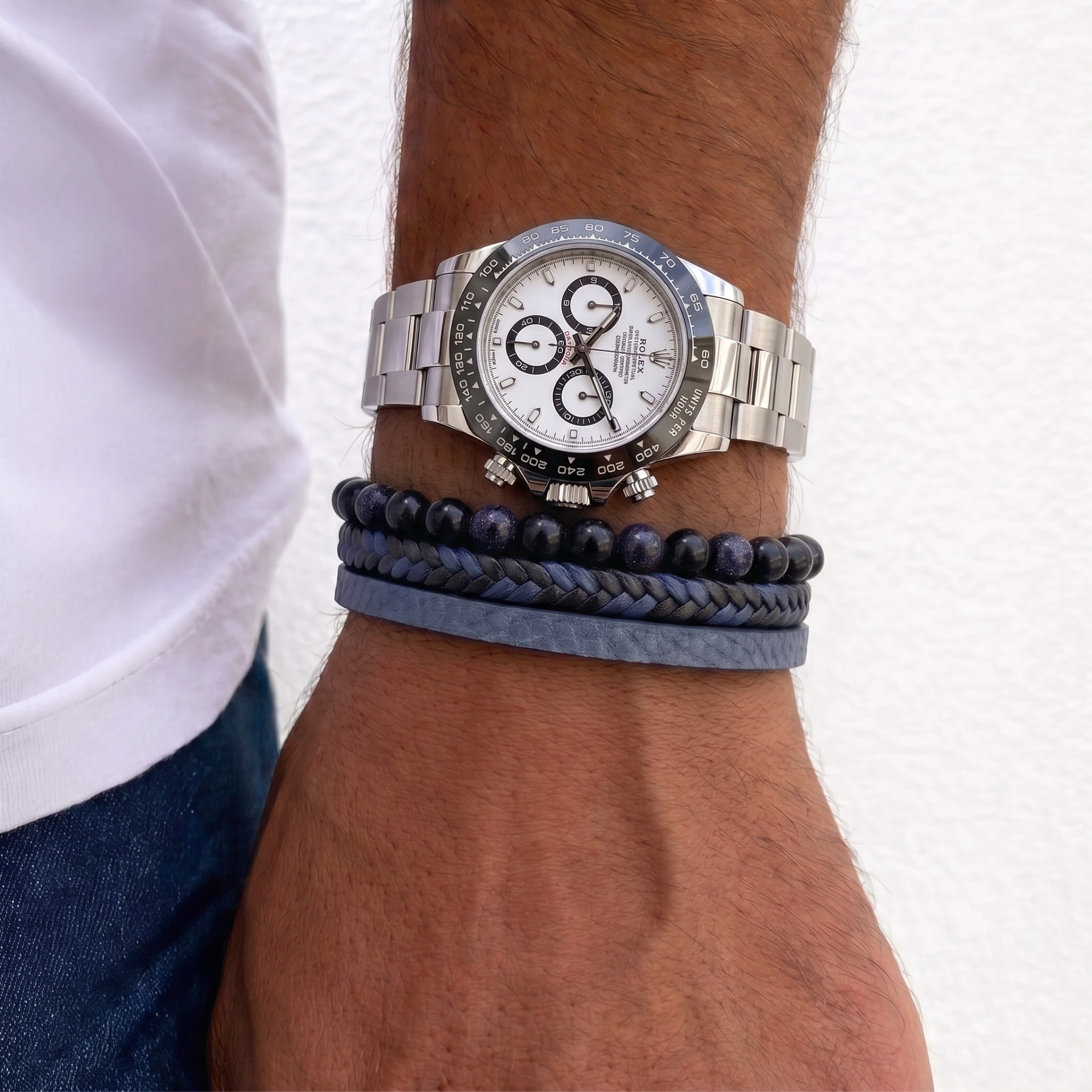 Close-up of a wrist wearing a steel watch with beaded, braided and leather bracelets